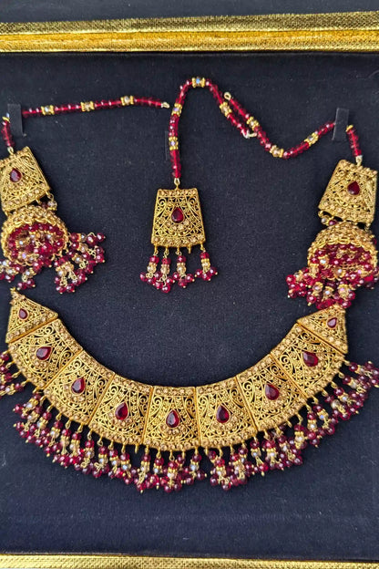 Golden necklace with red stones on a dark background
