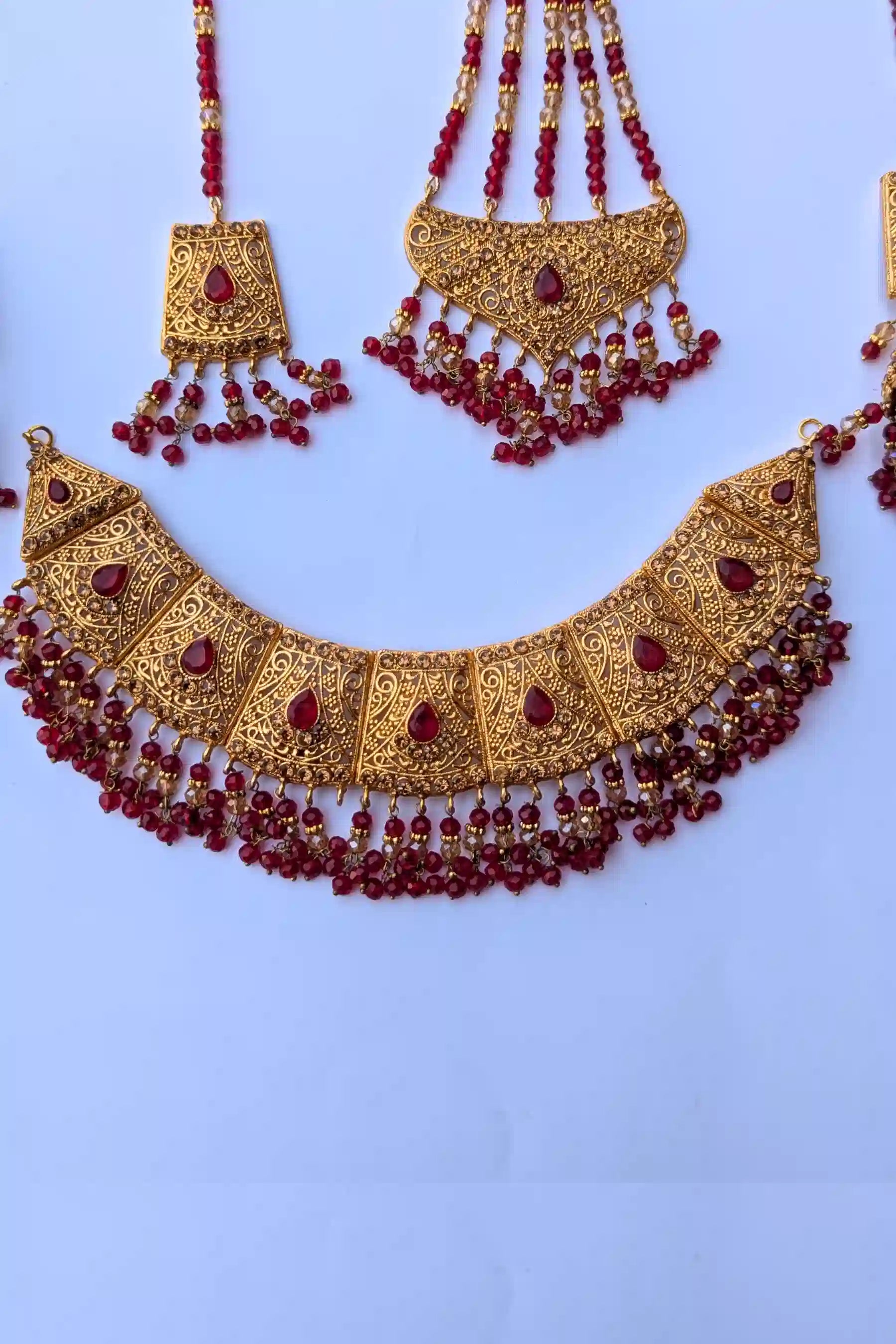 Gold necklace with red beads on a light blue background