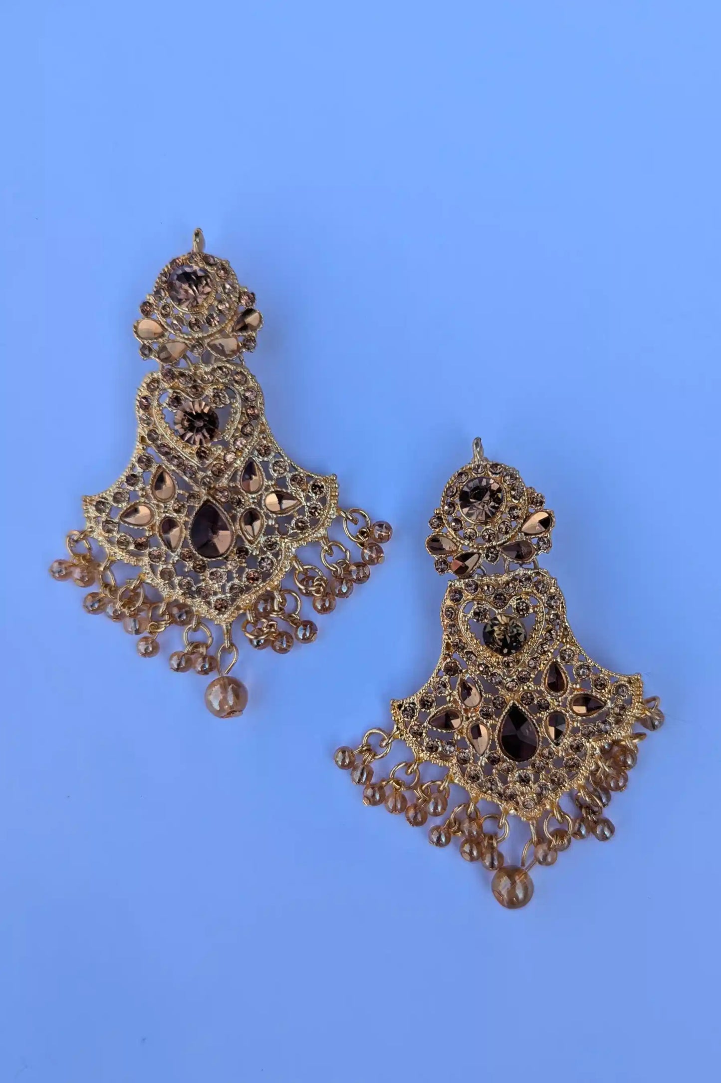 Ornate gold earrings with black stones on a blue background
