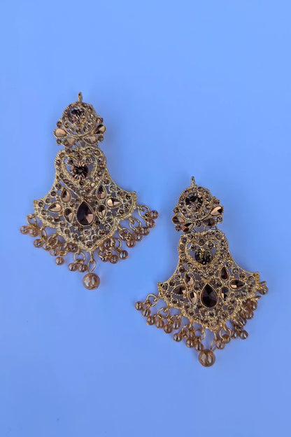 Ornate gold earrings with black stones on a blue background