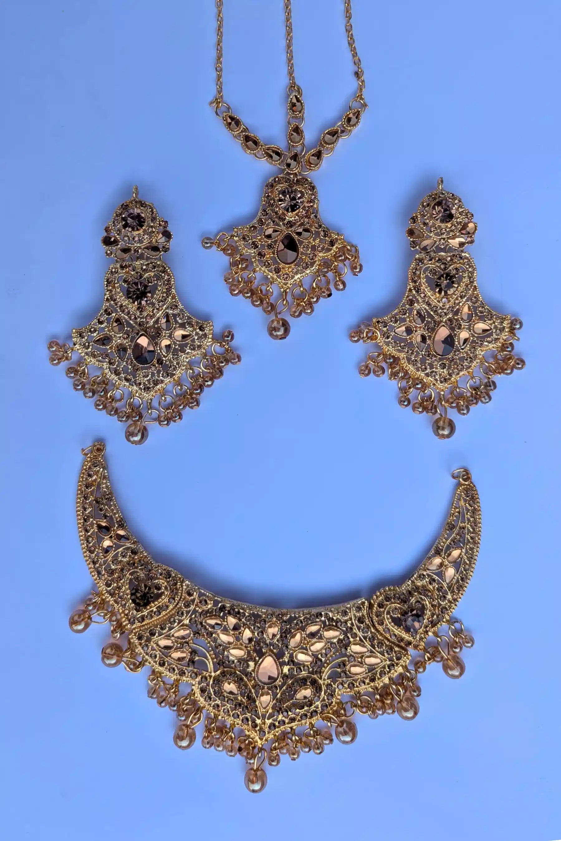 Ornate gold necklace and earrings on a blue background