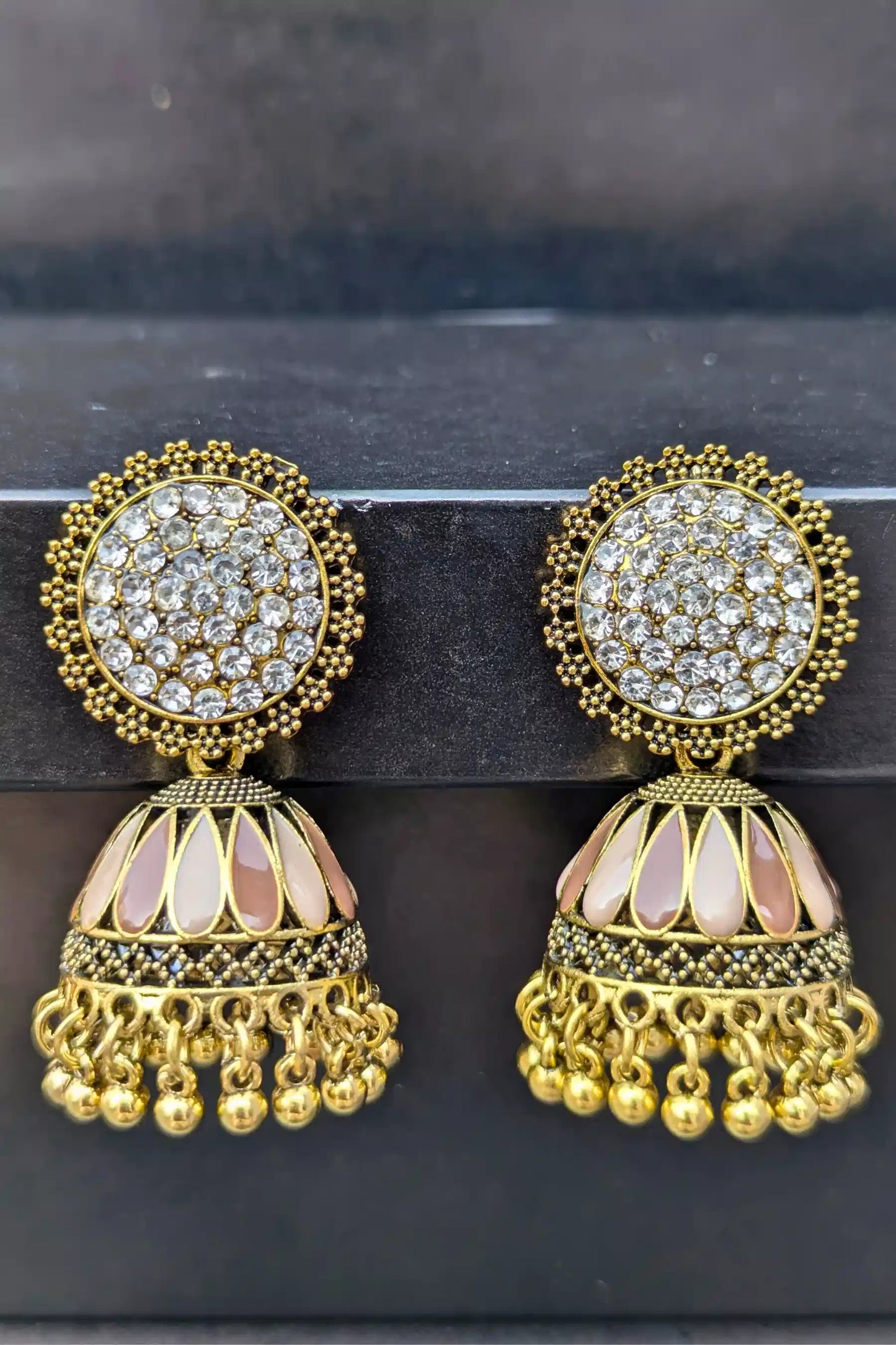 Pair of gold and crystal earrings on a dark background