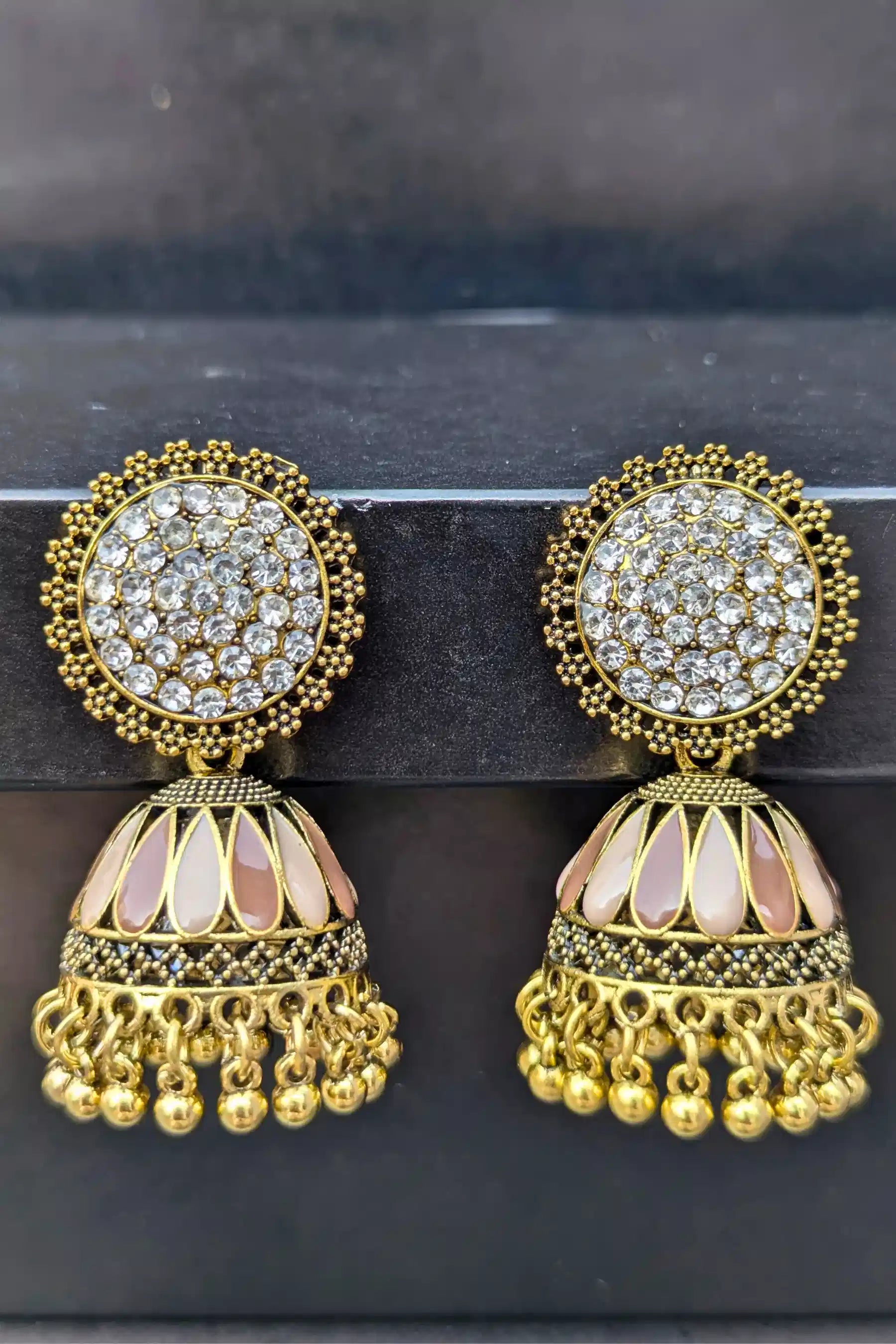 Pair of gold and crystal earrings on a dark background