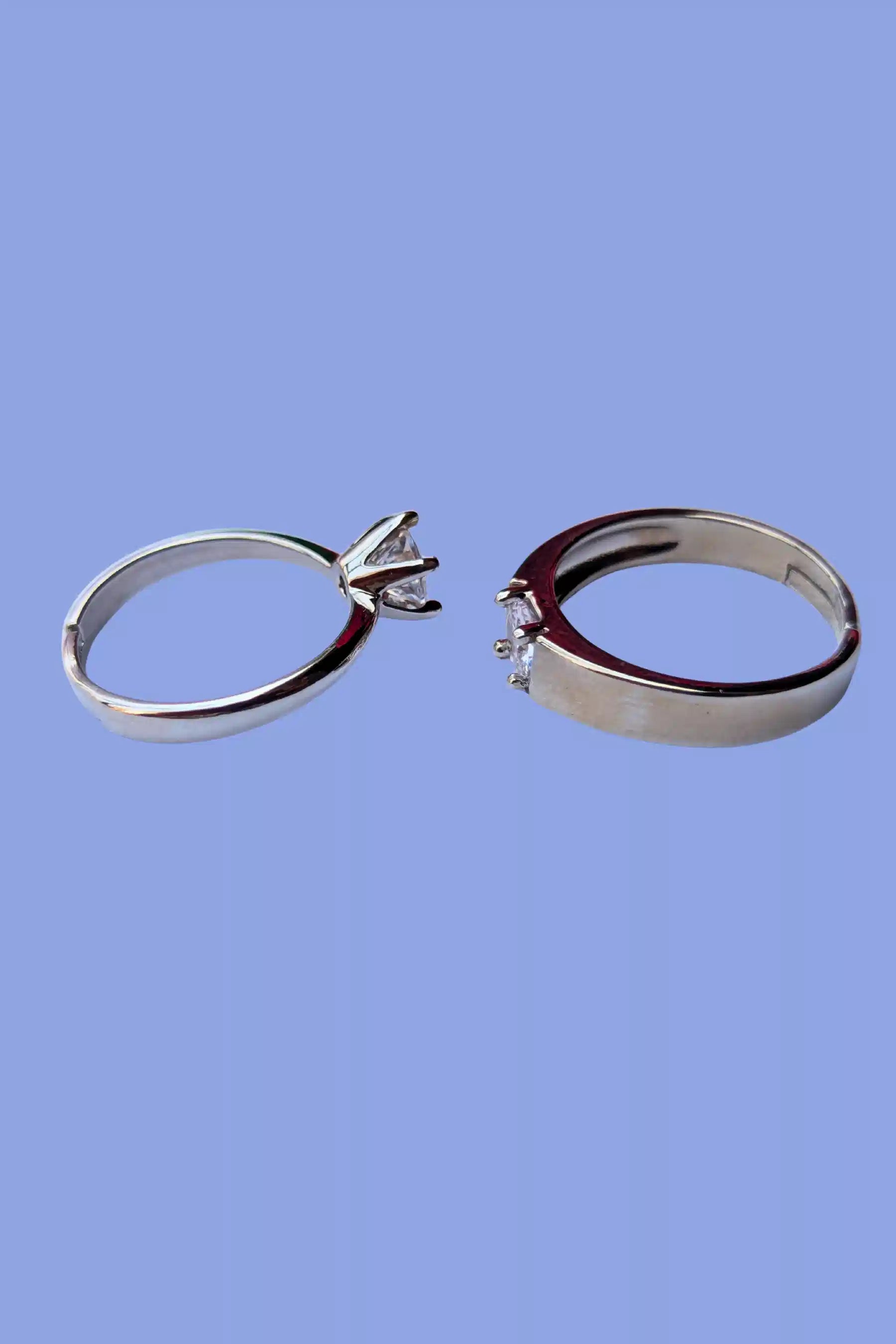 Two silver rings with diamond settings on a blue background