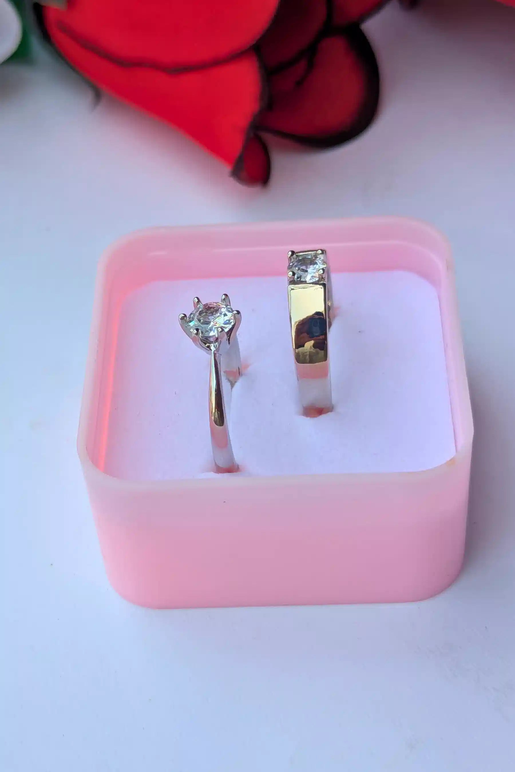 couple rings with gemstones in a pink jewelry box on a white background