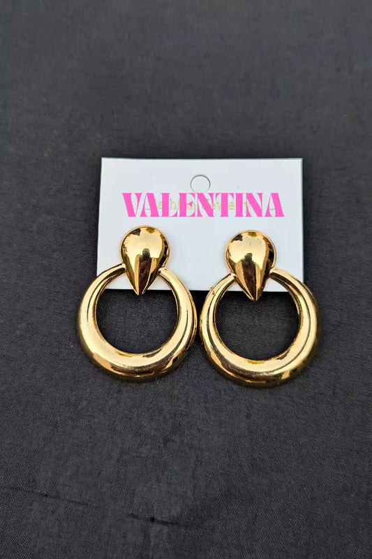 Gold hoop earrings on a Valentina branded card against a dark background