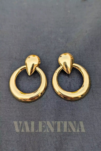 Gold hoop earrings on a dark gray background with 'Valentina' branding.