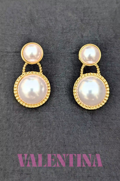 Pair of pearl earrings with gold accents on a gray background, branded 'Valentina'.