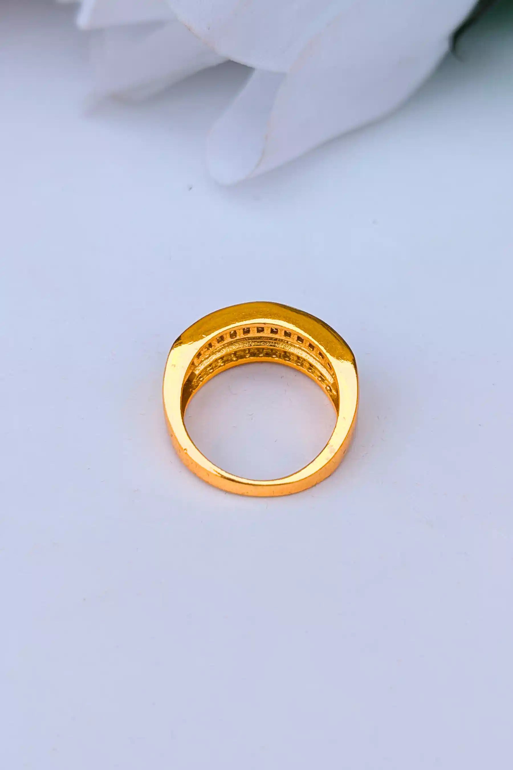 Gold ring with embedded stones on a light gray background