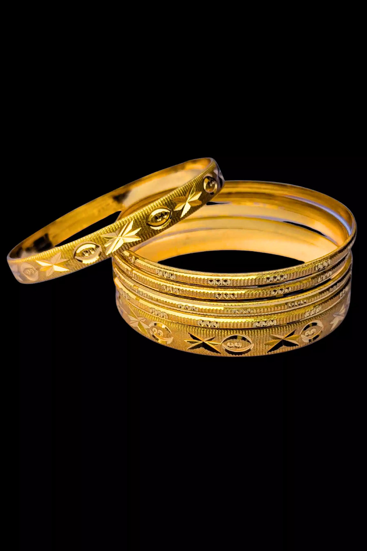 Set of gold bangles with intricate designs on a black background