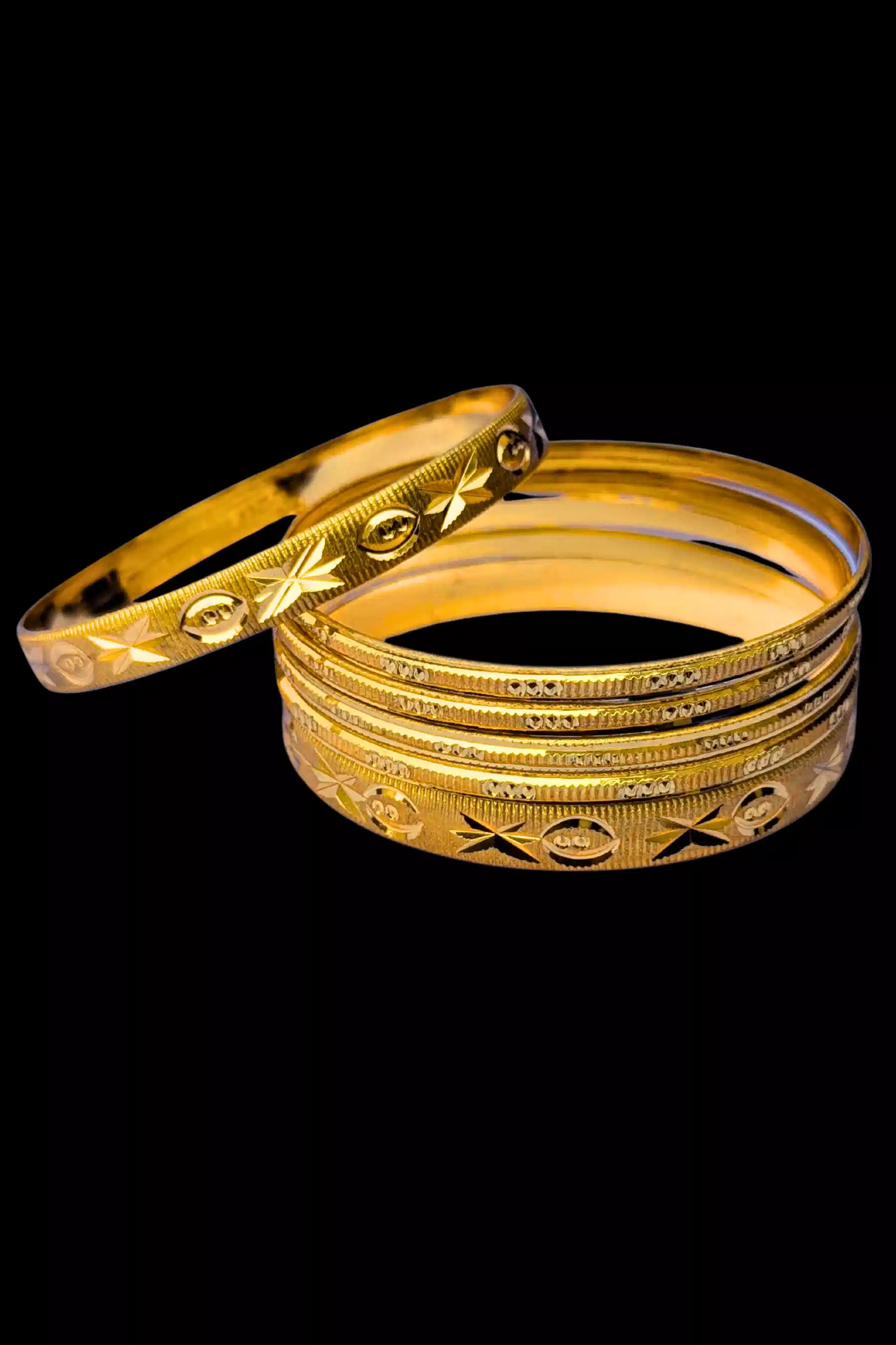 Set of gold bangles with intricate designs on a black background