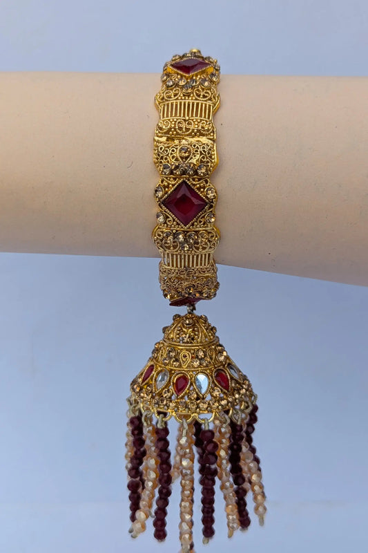 Decorative gold bracelet with red stones on a plain background