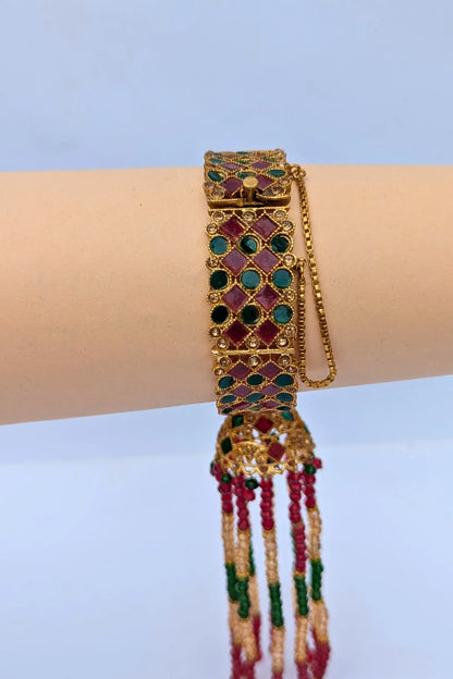 Decorative bracelet with gemstones and beads on a wrist against a light blue background