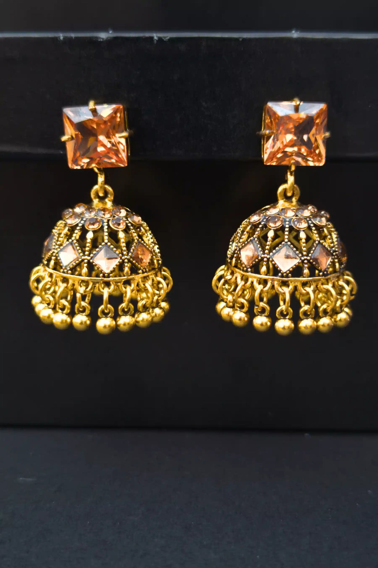 Gold earrings with champagne gemstones on a black background