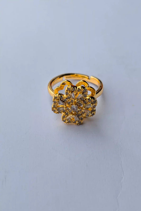 Gold ring with floral design on a light gray background