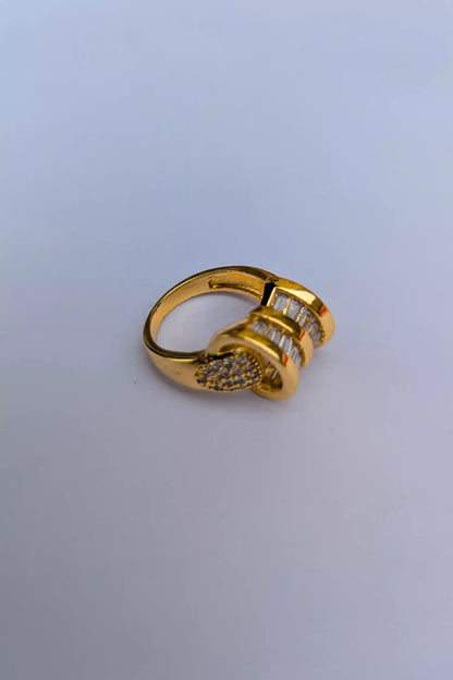 Gold ring with embedded stones on a light gray background