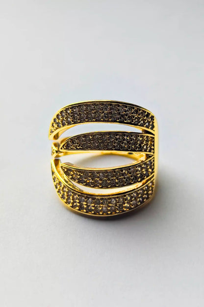 Gold ring with black gemstones on a light gray background