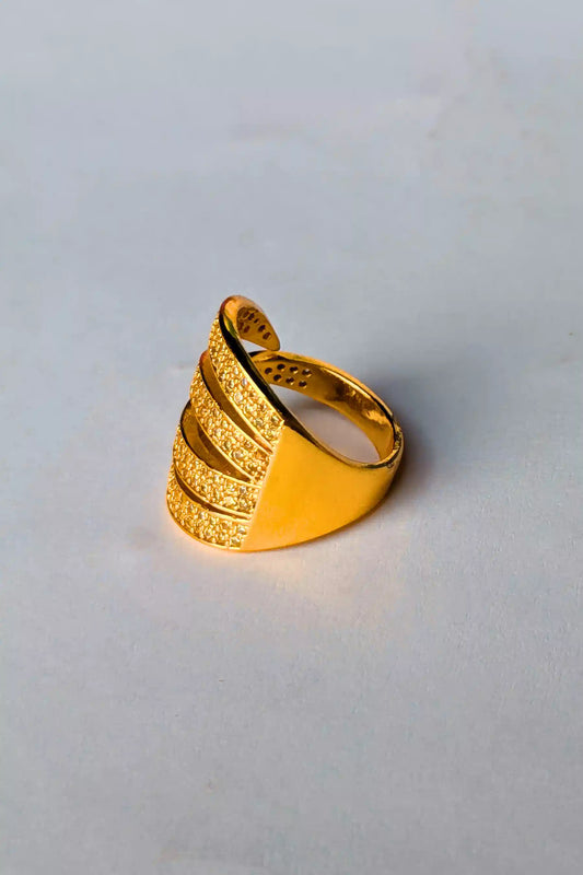 Gold ring with a textured design on a light gray background
