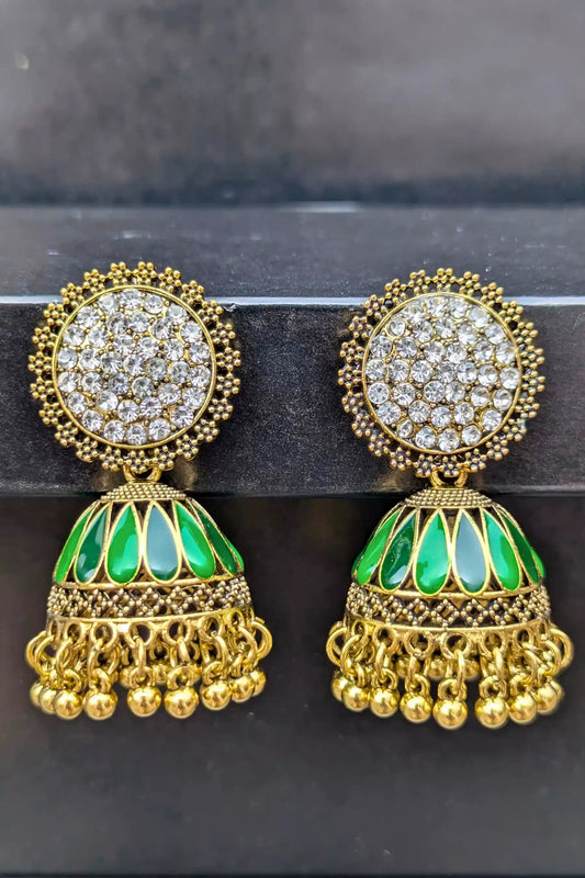 Gold and green earrings with intricate designs on a dark background