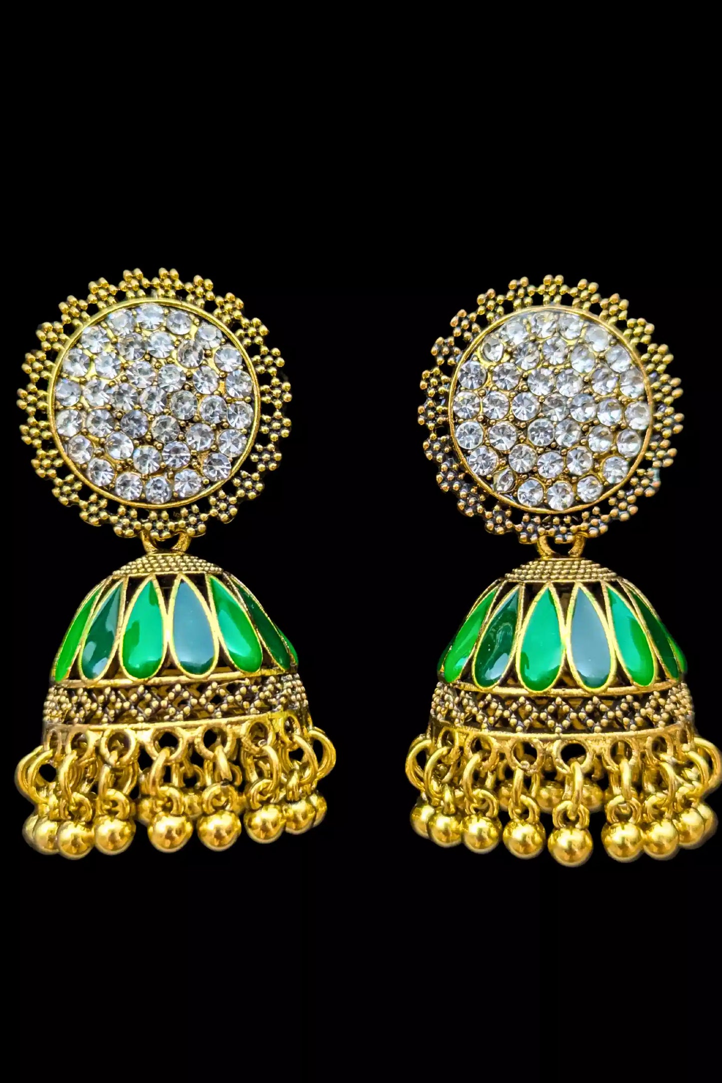 Gold earrings with green stones on a black background