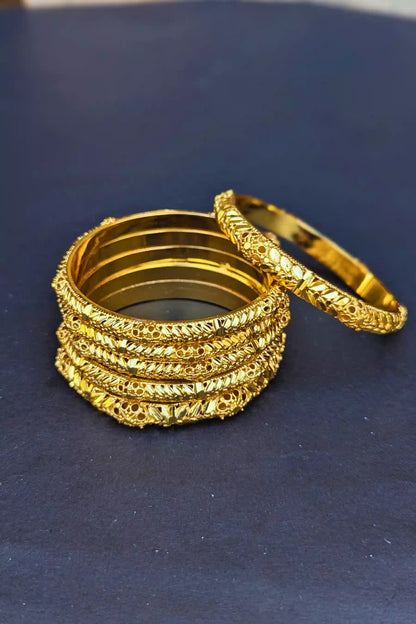 Set of gold bangles on a dark blue background