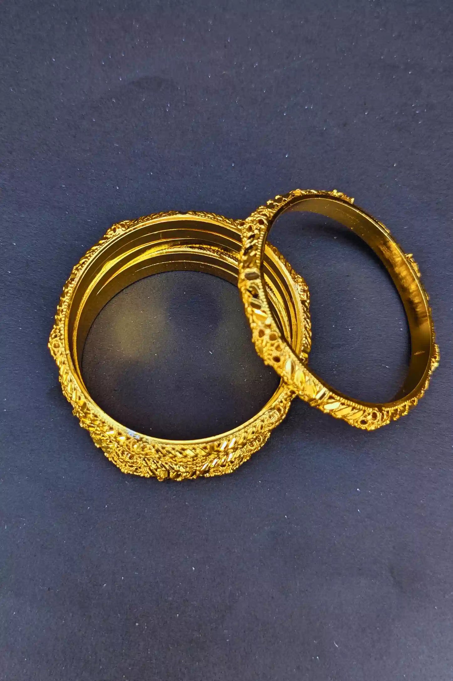 Two gold bangles on a dark blue background