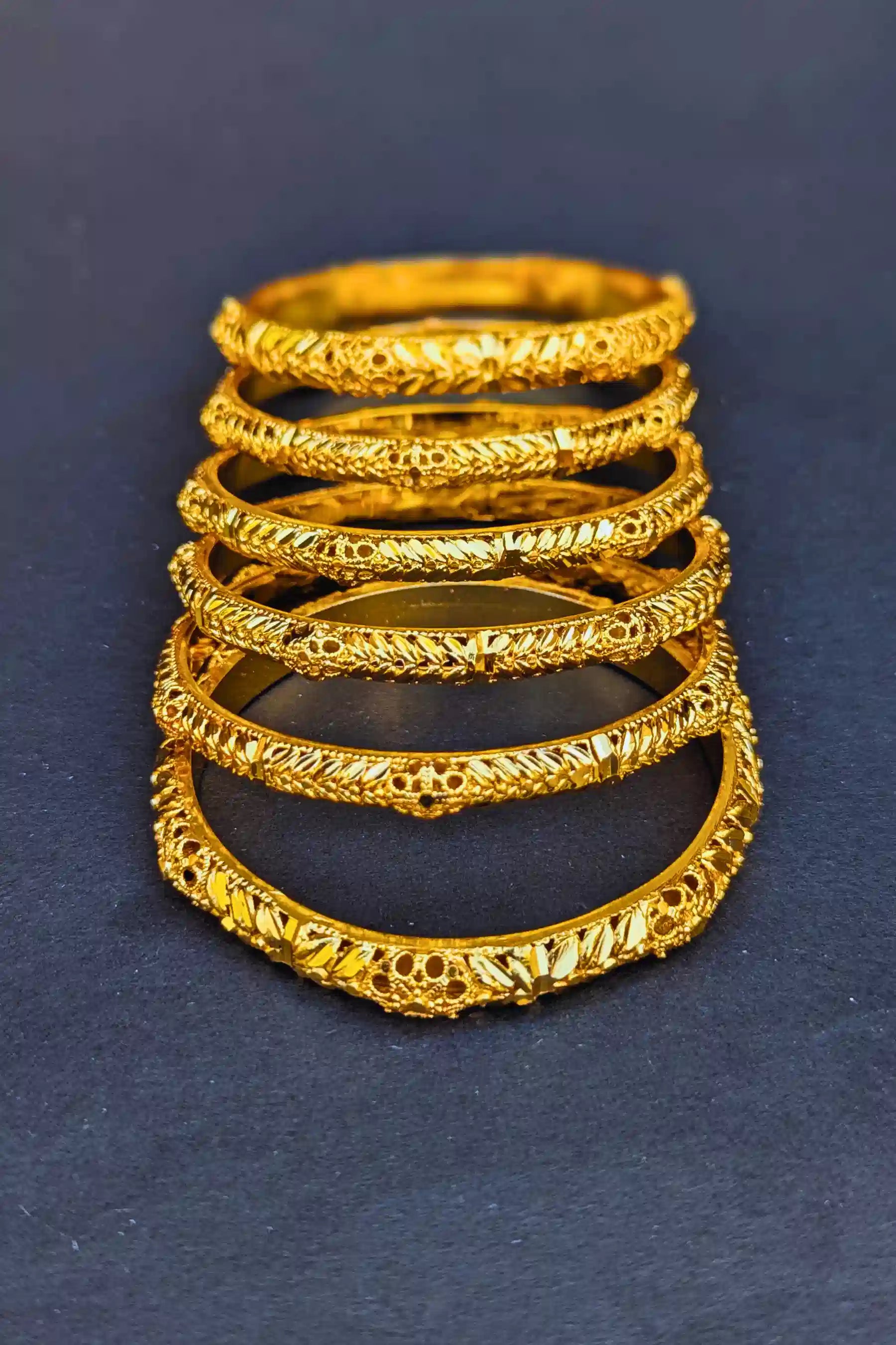 Set of gold rings stacked on a dark blue background