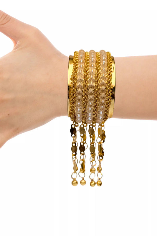 Gold bracelet with beads and chain on a wrist against a white background