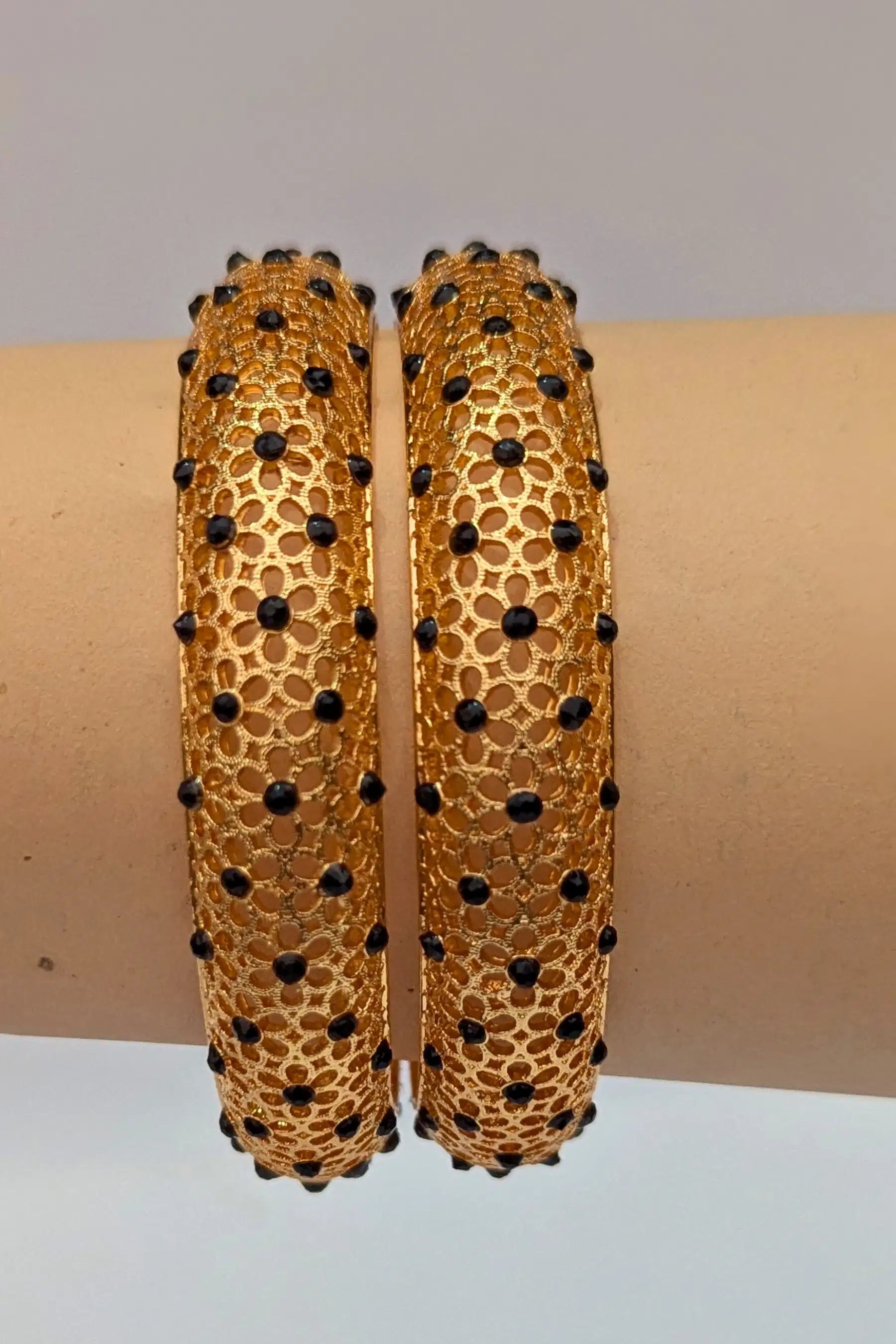 Gold bangles with black stones on a hand