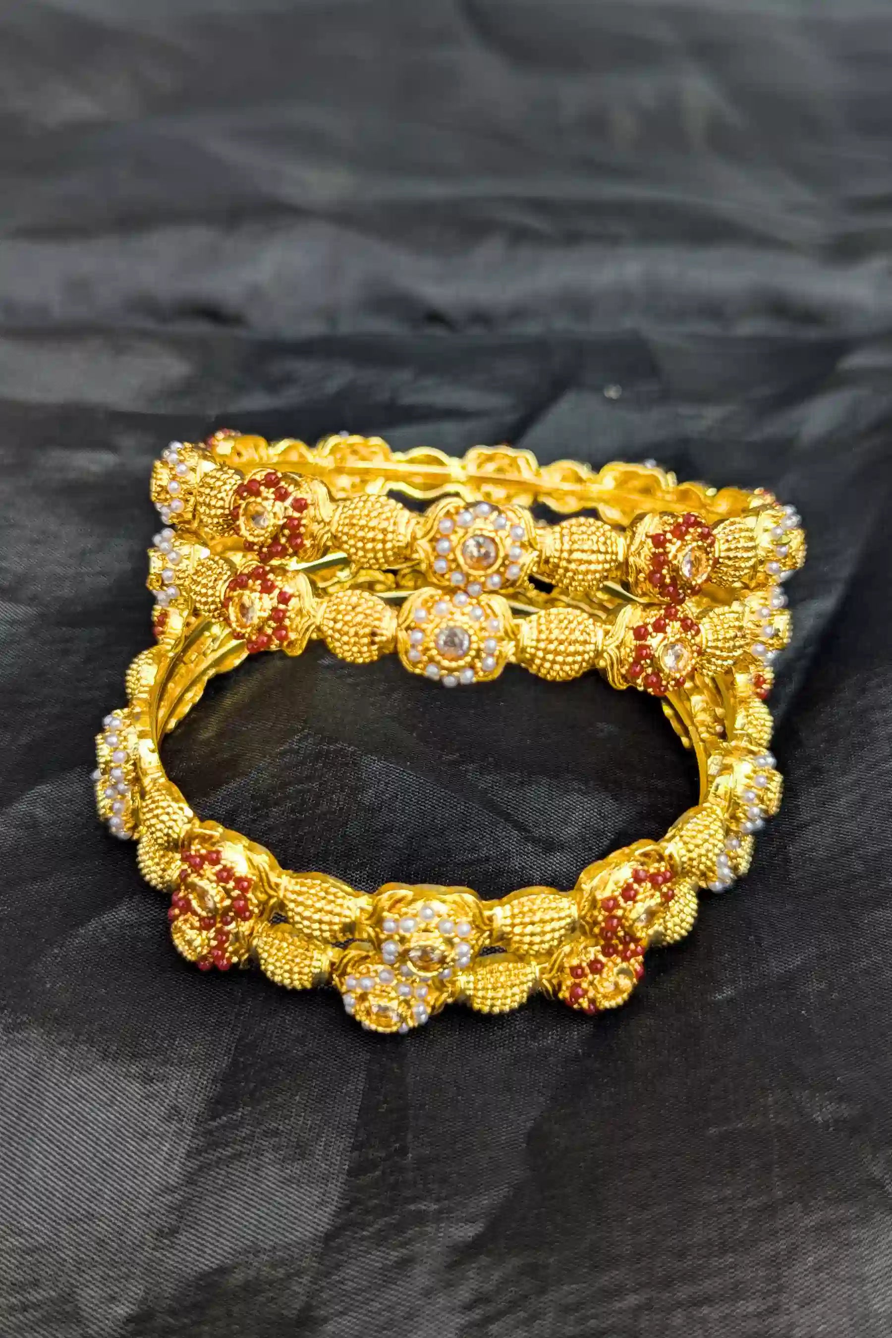 Gold bracelet with floral design on a black fabric background