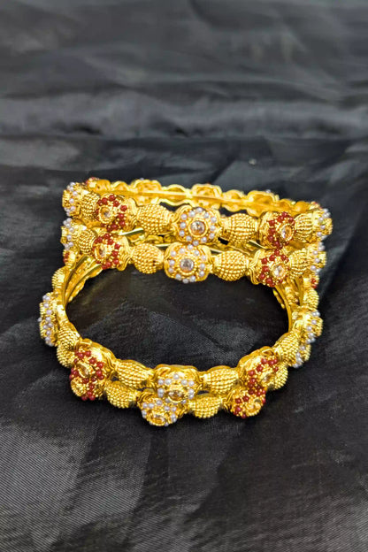 Gold bracelet with floral design on a black fabric background