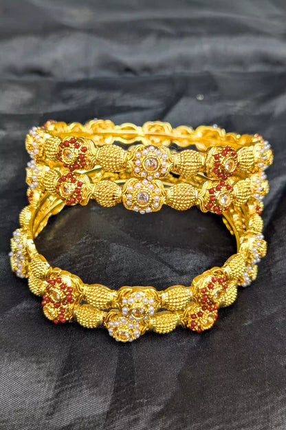 Gold bracelet with floral designs on a black fabric background