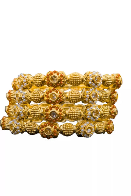 Set of gold bangles with intricate designs on a white background