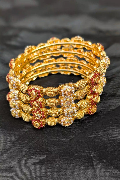 Set of gold and red beaded bracelets on a black fabric background