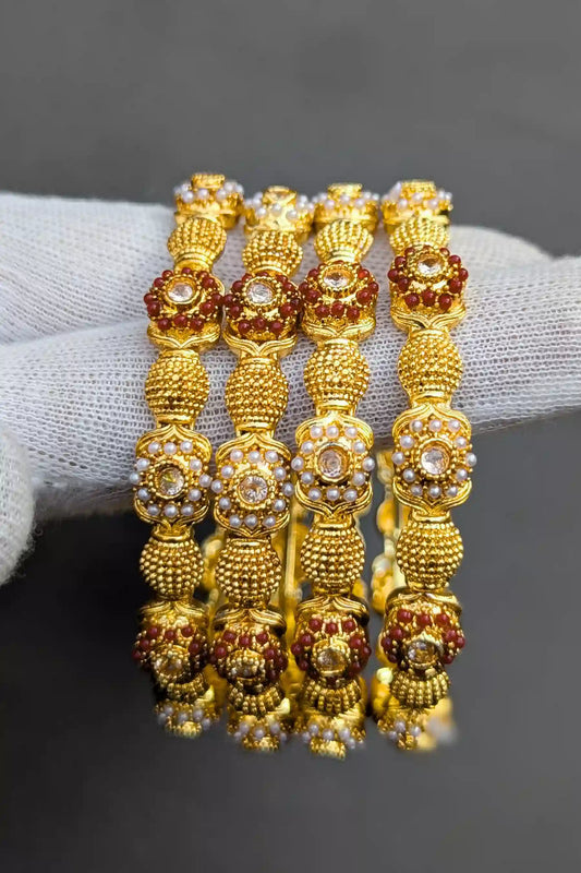 Set of gold and red beaded bracelets on a gray surface