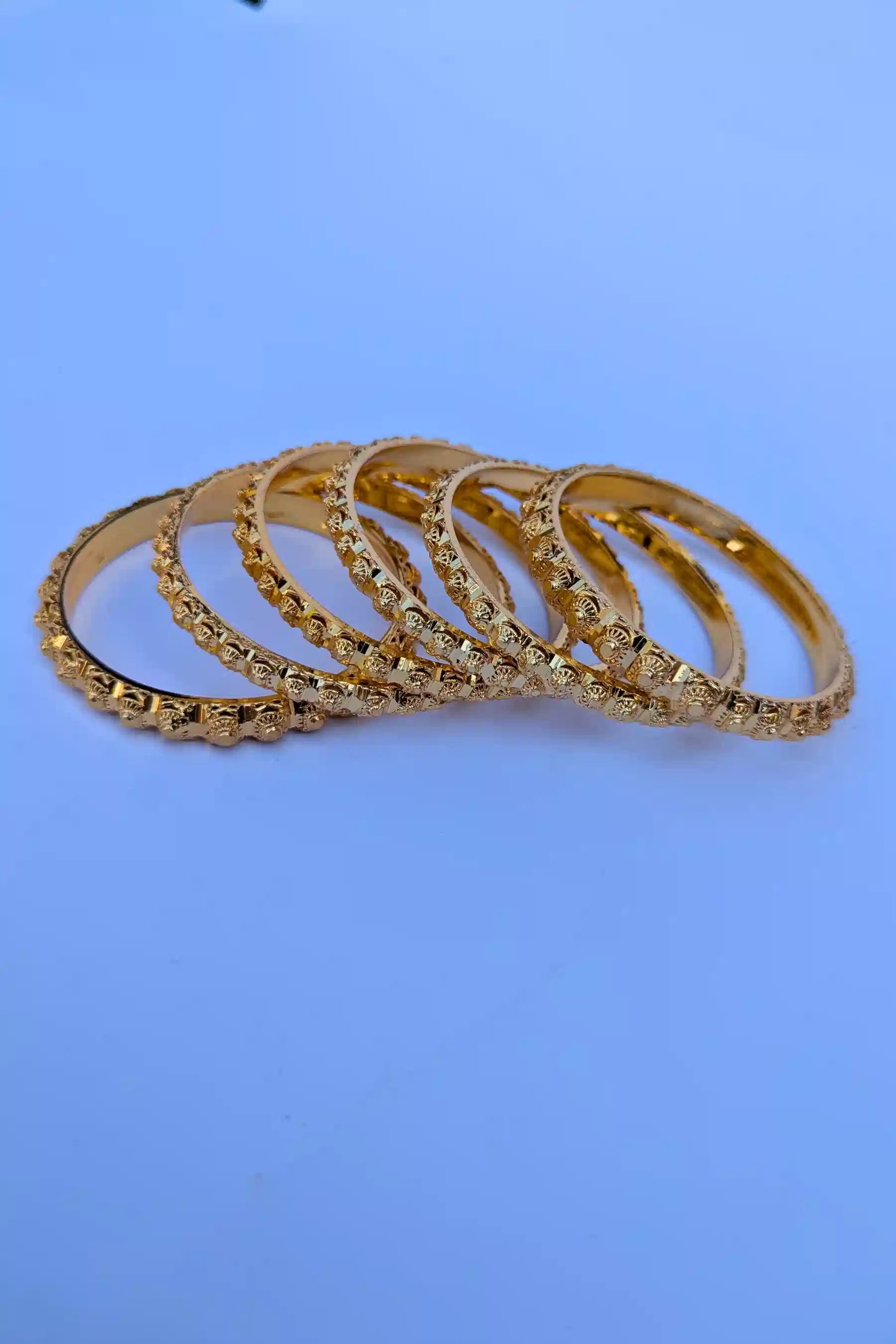 Set of gold bangles on a blue background