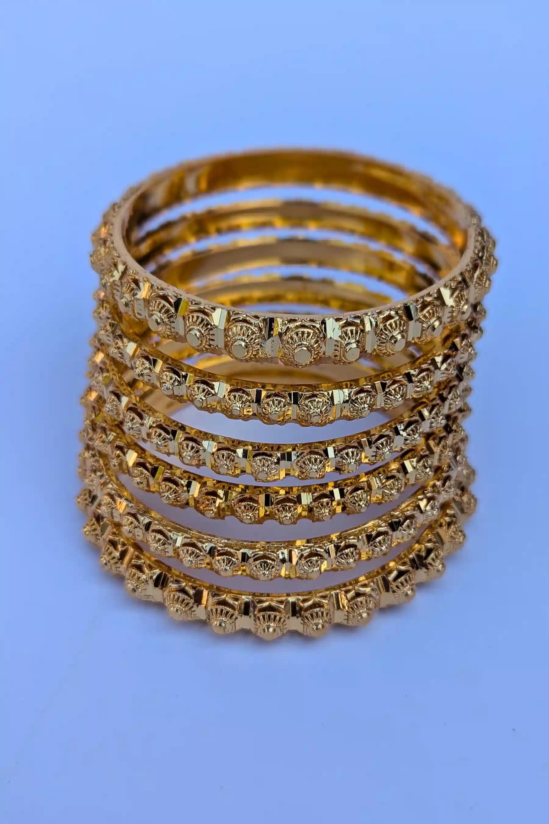 Set of gold bangles on a blue background
