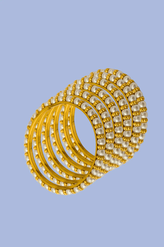 Set of gold and pearl bangles on a light blue background