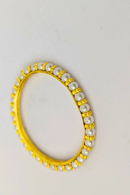 Gold and pearl bracelet on a light gray background
