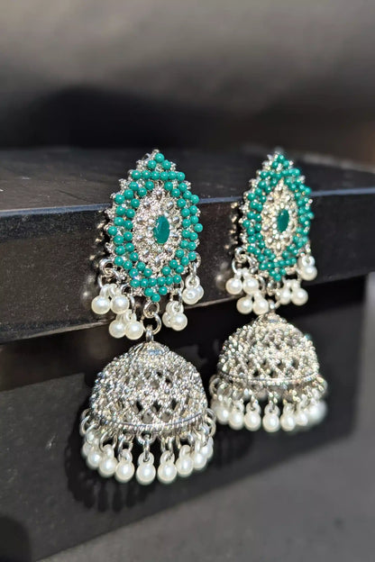 Pair of earrings with turquoise stones and pearl-like beads on a dark surface