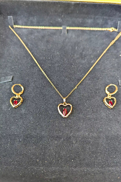 Gold heart-shaped necklace and earrings on a black background