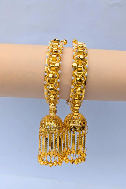 Golden bangles with tassels on a mannequin arm against a light blue background