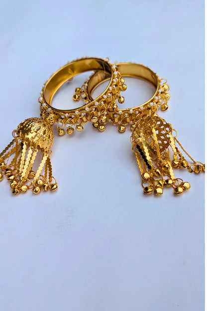 Gold bangles with decorative elements on a light blue background