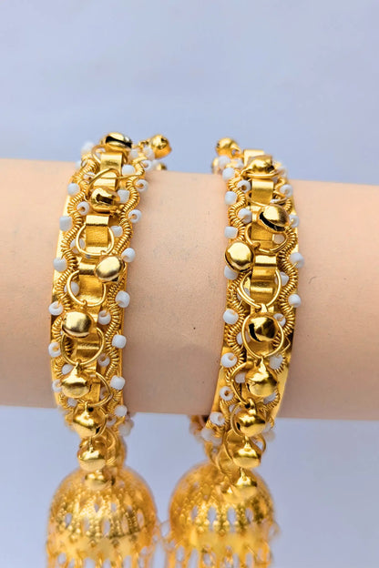 Gold bangles with white beads on a light blue background