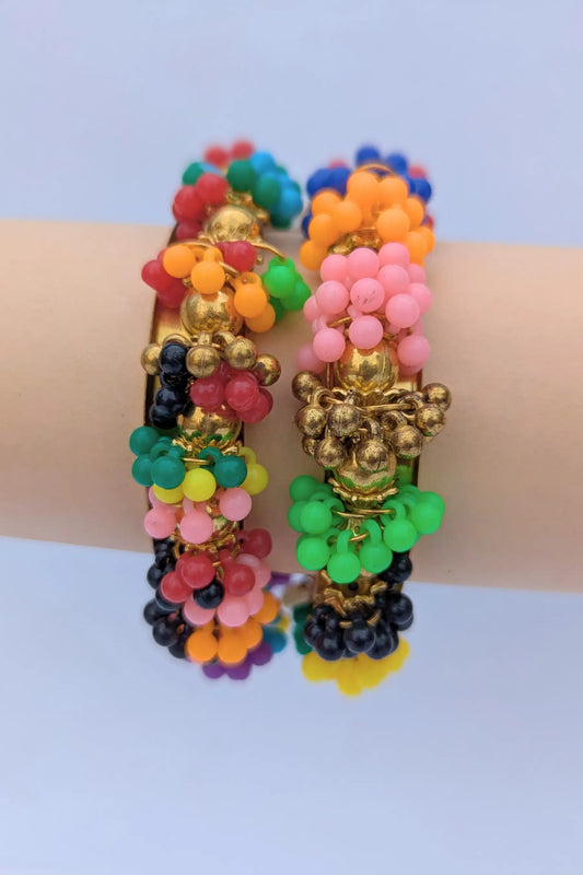 Colorful beaded bracelets on a wrist against a light blue background