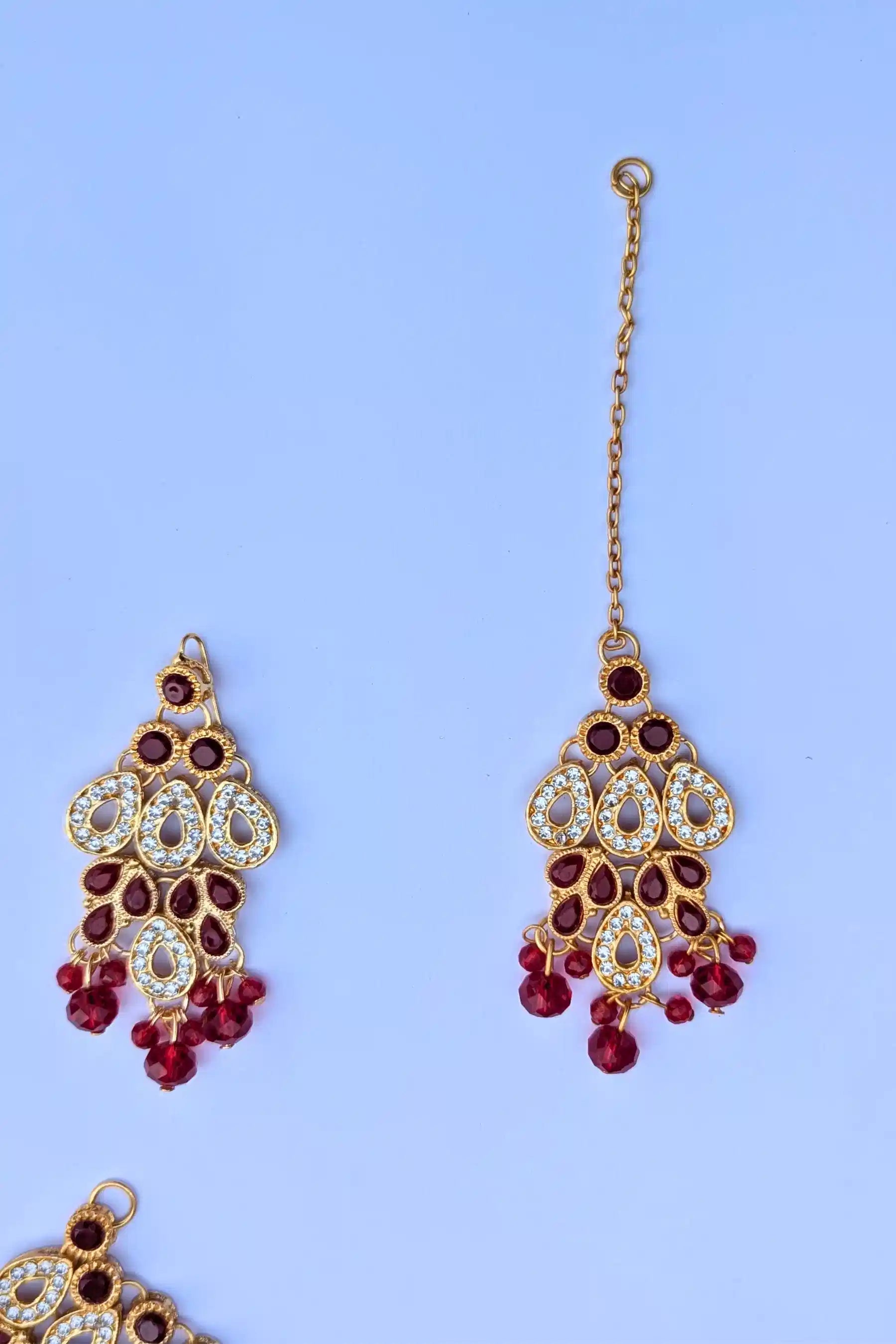 Decorative earrings with red and gold details on a light blue background