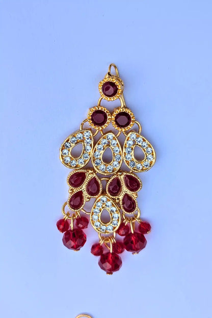 Gold and red earring on a light blue background