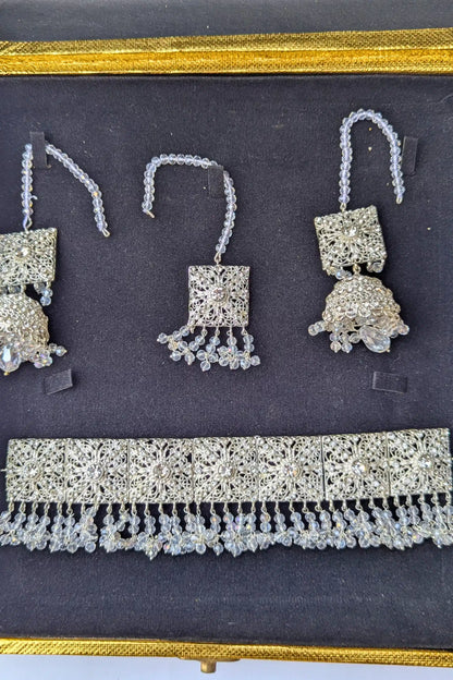 Set of silver jewelry including earrings and a necklace on a dark background
