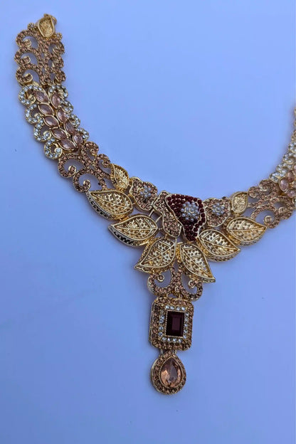 Ornate gold necklace with gemstones on a light blue background