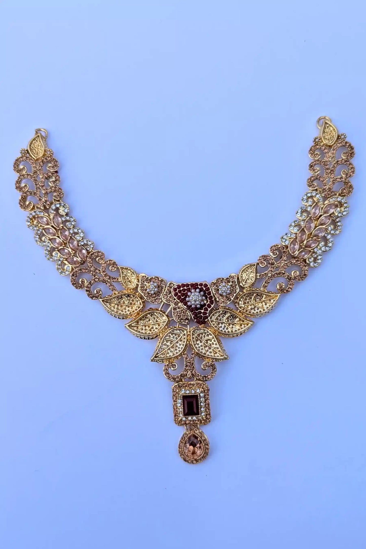 Gold necklace with intricate design on a light blue background